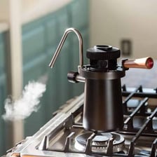 A barista using an espresso machine’s steam wand to froth milk