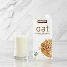 Glass and carton of oat milk beside oats