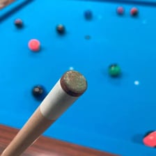 The leather tip of a pool cue near a billiard ball