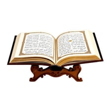 An open Quran displayed on an ornate reading stand.