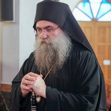 An abbot standing with monks inside a monastery.