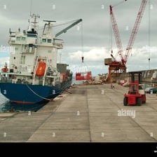 A cargo ship docked beside a quay while cargo is unloaded
