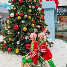 A holiday elf working in a decorated shopping mall.