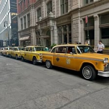 A yellow taxi cab driving on a city street.
