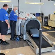 Airport security officer screening a passenger bag