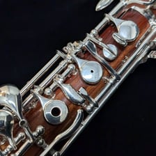 A slender wooden oboe with keys and a reed