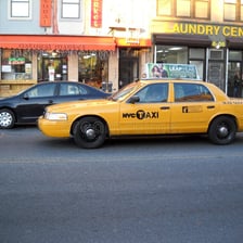A yellow New York City taxi picking up a passenger