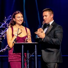 An awards show host speaking into a microphone