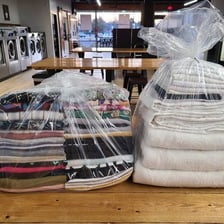 Clean folded clothing associated with a wash-and-fold laundry service.