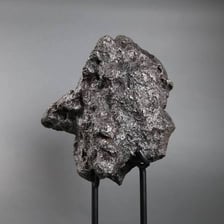 A dark iron meteorite specimen displayed as a rock sample.
