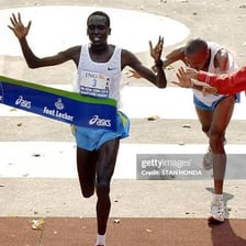 A marathon runner breaking through a finish-line tape