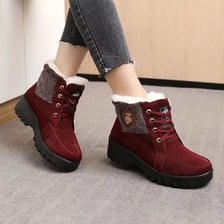 Snow reaching approximately ankle height around a person’s boots.