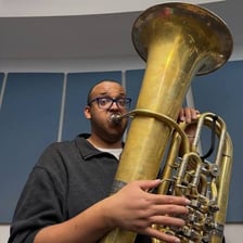 A musician holds a large brass tuba.