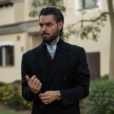 A wide ascot tie worn around the neck with formal clothing