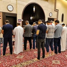 An imam leading worshippers in prayer inside a mosque