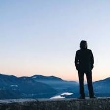 A person viewing a distant mountain from a lookout.