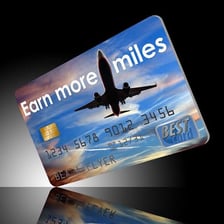An airline rewards card displayed beside an airplane.