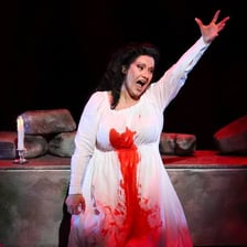 An actor delivering a sorrowful dramatic line onstage.