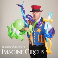 A circus performer juggling while making balloon animals