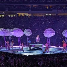 A musician performing onstage in a large concert arena