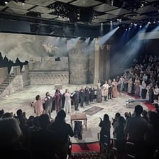 A female opera singer performing onstage before an applauding audience.