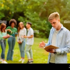 A shy person standing somewhat apart from a group.