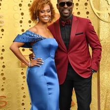 Two celebrities posing together as a couple on a red carpet.