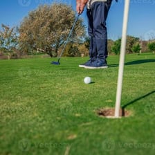 A golfer putting toward a hole on a golf green.