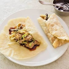 A plate of moo shu pork served with thin pancakes.