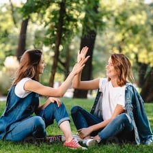 Two people exchanging a high five with their hands raised.