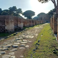 A road leading toward ancient Roman ruins.