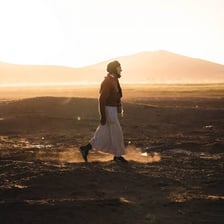 A nomadic traveler moving through a desert landscape