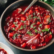 A red beet beside a bowl of red borscht