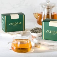 Cups and loose leaves representing oolong and Darjeeling tea.