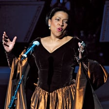 An opera singer performing a solo onstage.