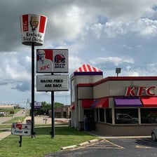 A KFC restaurant sign beside a serving of fried chicken.