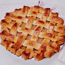 A baked fruit pie topped with a woven lattice crust