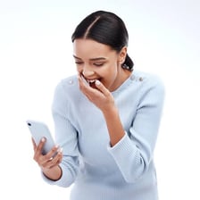A person laughing while looking at a phone message