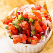A bowl of pico de gallo made with chopped tomatoes, onions, cilantro, and peppers.