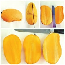 A ripe mango shown whole and cut open to reveal its golden flesh and central pit.