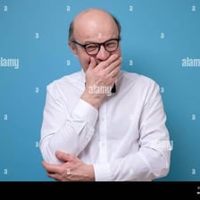 A person covering their mouth while making a quiet, snickering laugh.
