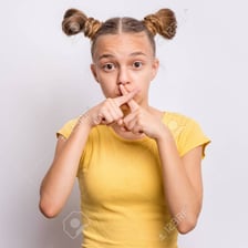 A person holding a finger to their lips to request silence