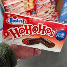 Packaged Ho Hos snack cakes shown in a Santa-themed setting.