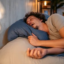 A sleeping person shown snoring in bed
