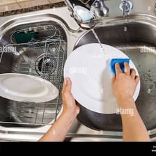 Hands holding an object under running water from a faucet.