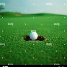 A golf ball at the edge of or dropping into a putting hole