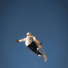 A snowboarder airborne above a snow jump