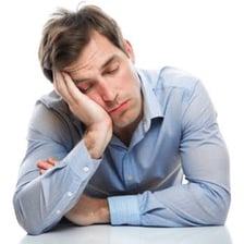 A tired person resting their head on one hand