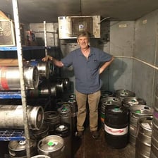 Several beer kegs arranged at a basement party
