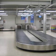 Suitcases traveling around an airport baggage carousel.